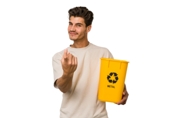 Young caucasian man holding a metal trash for recycle Young caucasian man holding recycling bins isolated on white background pointing with finger at you as if inviting come closer.