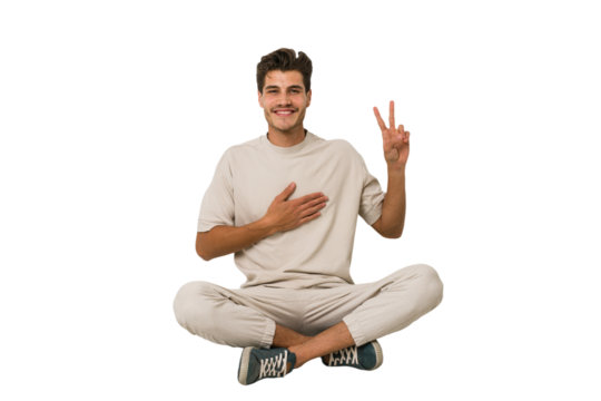 Young caucasian man sitting on the floor isolated on white background taking an oath, putting hand on chest.