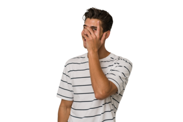 Young handsome caucasian man isolated on white background blink at the camera through fingers, embarrassed covering face.