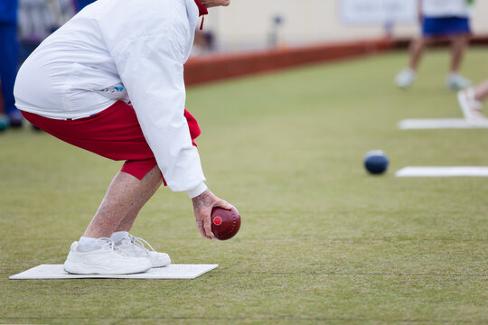 Elderly woman crouching before delivering a lawn bowl