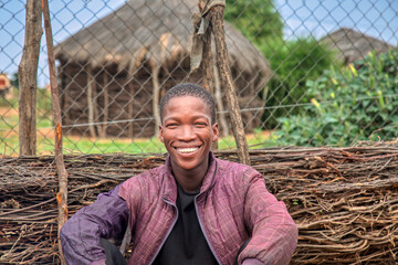 african village african man, in front of house , typical home with wire fencing , rural living