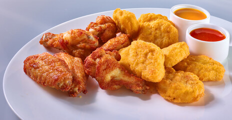 Panierte Haehnchenteile mit Dips auf weissem Teller, Hähnchennuggets, Fastfood, Geflügel, Chicken, 