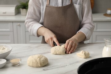 Making pretzels. Woman cutting dough at table in kitchen, closeup