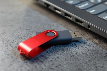 USB flash drive and laptop on dark grey table, closeup