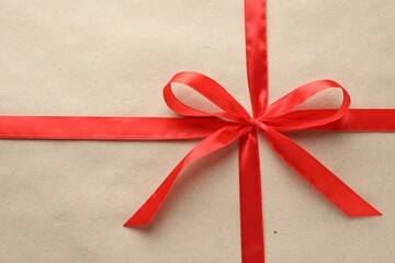 Gift wrapped in kraft paper and bow as background, top view