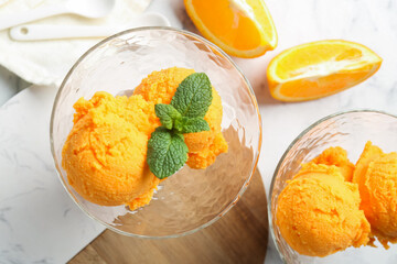 Balls of tasty orange sorbet in dessert bowls, fresh fruit and mint on white marble table, flat lay