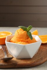 Balls of tasty orange sorbet, fresh fruit, mint and spoon on light table, closeup