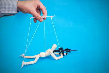 Male hand controlling with leading white thread a laying down sniper soldier with a rifle wooden...