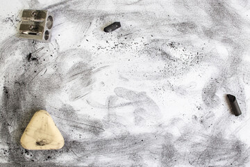 Black dust and smudges on white paper next to an eraser and a pencil sharpener