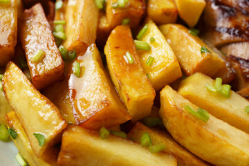 close-up fried country-style potatoes with herbs, unhealthy food, top view