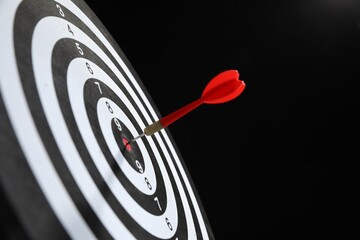 Targeting. Dart board with arrow on black background, closeup