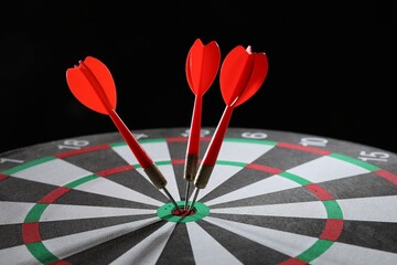 Targeting. Dart board with arrows on black background, closeup