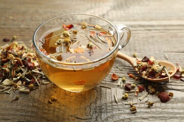Delicious herbal tea and dry leaves on wooden table, closeup