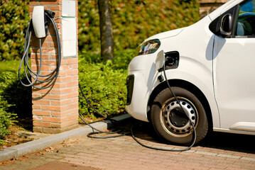 Electric Delivery Van Charging at Residential EV Station in Green Surroundings