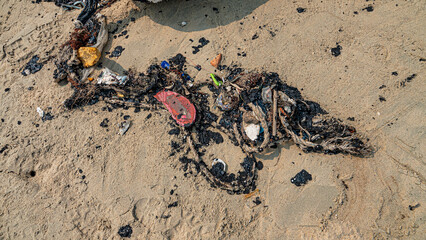 Obraz premium Oil pollution of sea, coast. Floating objects (flotsam, fragments of fishing nets) are covered with fuel oil and bring toxin to other parts of sea, secondary pollution. South China Sea