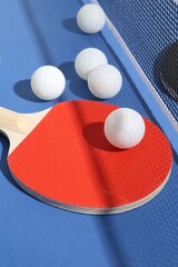 Ping pong racket, balls and net on blue background, closeup