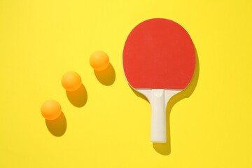 Ping pong racket and balls on yellow background, flat lay