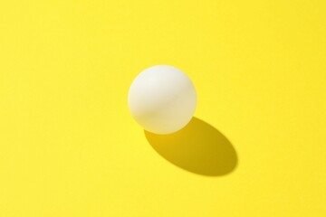 One ping pong ball on yellow background, closeup