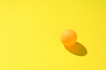 One ping pong ball on yellow background. Space for text