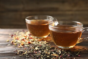 Refreshing herbal tea and dry leaves on wooden table, closeup