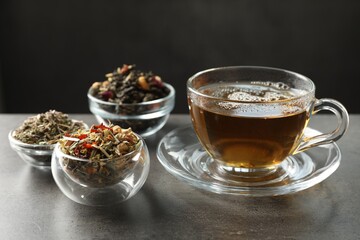 Refreshing herbal tea and dry leaves on grey table, closeup
