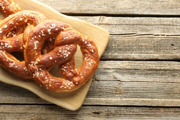 Tasty pretzels with salt on wooden table, top view. Space for text