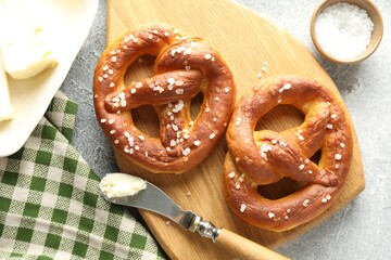 Tasty pretzels with salt and butter on light grey table, flat lay