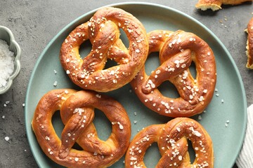 Tasty pretzels with salt on grey table, flat lay
