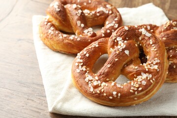 Tasty pretzels with salt on wooden table, closeup. Space for text
