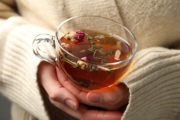 Woman with glass cup of aromatic herbal tea, closeup