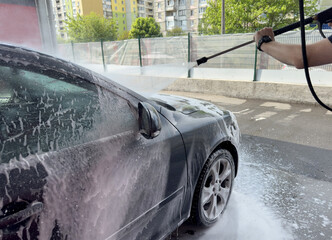 Closeup of male driver washing his car with contactless high pressure water jet
