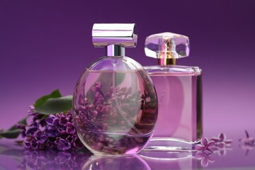Bottles with perfumes and lilac flowers on mirror surface against color gradient background, closeup