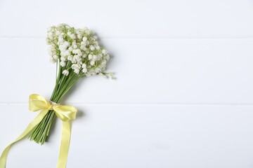 Bouquet of beautiful lily-of-the-valley flowers on white wooden background, top view. Space for text