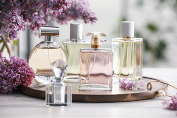 Bottles of perfumes and lilac flowers on white wooden table, closeup