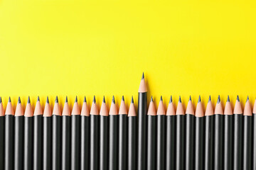 Many sharp graphite pencils on yellow background, flat lay. Space for text