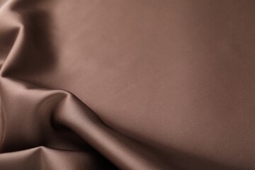 Crumpled light brown silk fabric as background, closeup
