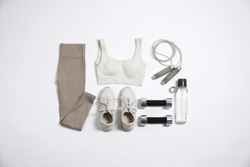 Sportswear, sneakers, dumbbells, skipping rope and water bottle on white background, flat lay