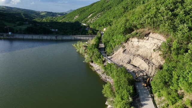 Terrain landslide due to spring heavy rains blocks provincial road 21 near Vernasca Mignano dam and basin with heavy machinery clearing debris, PC, Italy
