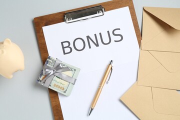 Clipboard with word Bonus, envelopes, money and piggybank on light grey background, flat lay