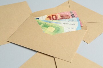 Money bonus. Envelopes with euro banknotes on light grey background, closeup