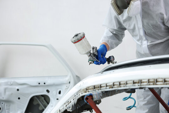 Worker painting car in body shop, closeup