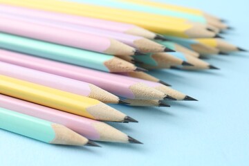 Many graphite pencils on light blue background, closeup