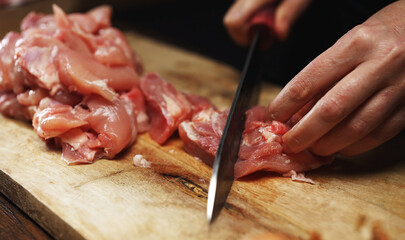 Female Chef Cutting Chicken Thighs with Knife.