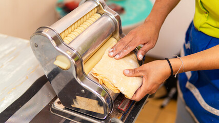 Young woman making homemade pasta with and old pasta maker 