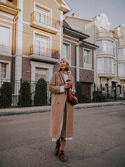 Beautiful young woman in coat walking around european city