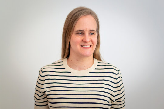 A visually impaired woman standing against white wall