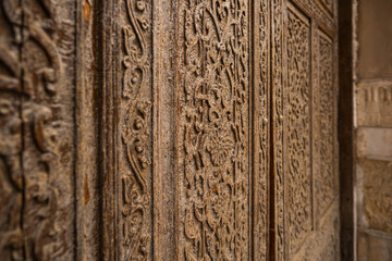 Traditional Islamic wooden door with intricate carved floral and geometric patterns close up, antique handcrafted design detail in historic architecture of Central Asia, cultural heritage texture