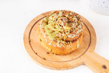 Trendy Dubai chocolate Cinnabon, cinnamon roll with with green pistachio frosting topping, Dubai chocolate filling and sprinkled with kataifi and pistachio nuts