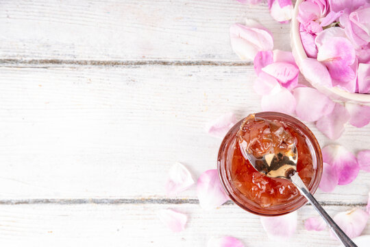 Rose petals jam, sweet tasty flower dessert, homemade confiture preserves with organic dessert roses petals, sugar and honey, in small jar on white table. Alternative medicine, remedies for sore throa
