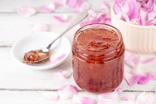 Rose petals jam, sweet tasty flower dessert, homemade confiture preserves with organic dessert roses petals, sugar and honey, in small jar on white table. Alternative medicine, remedies for sore throa